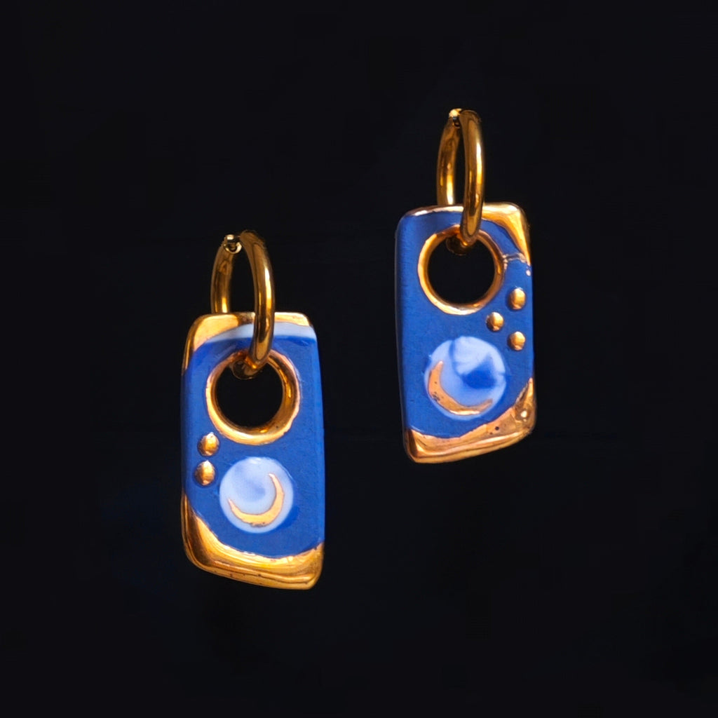 Pair of blue and gold earrings on a black background
